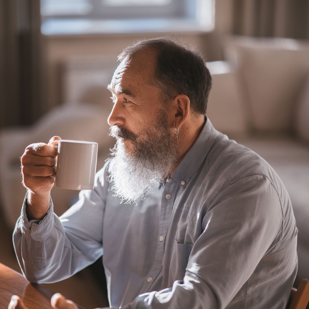 A man sitting at home with a cup of coffee, thinking something through